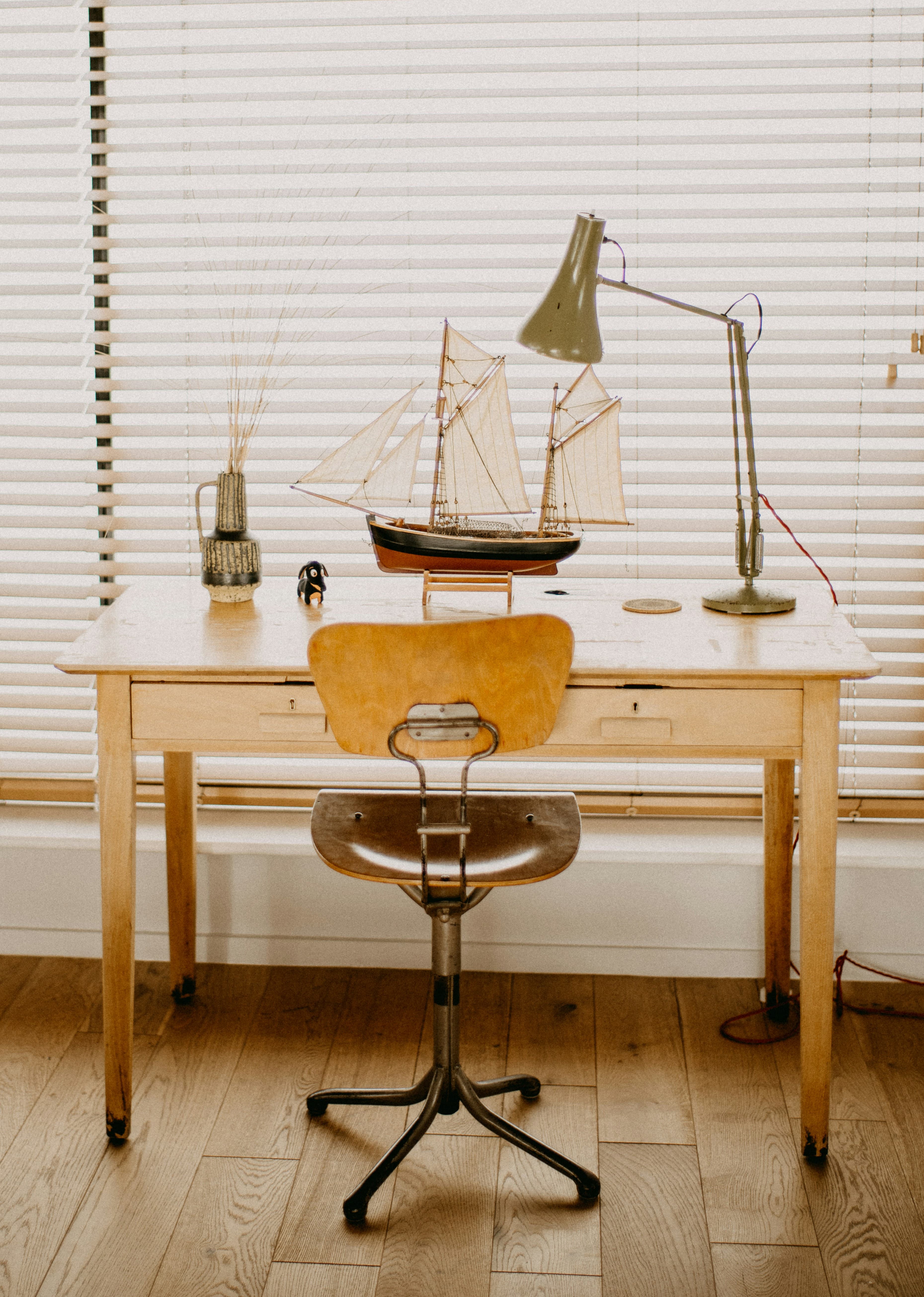 A workspace with a vintage desk, model schooner, and anglepoise lamp